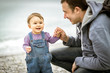 © scaliger - Happy father and one-year baby on beach, toddler plays outdoor