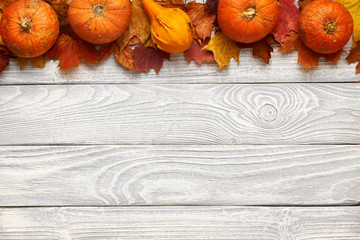 Wall Mural - Autumn leaves and pumpkins over old wooden background