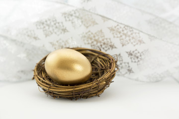 Celebration with gold nest egg in front of white ribbons