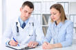 © rogerphoto - Doctor  and  patient sitting at the table in medical cabinet. High level and quality medical service concept.