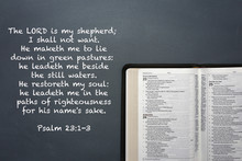 An Opened Bible On A Dark Chalkboard Surface