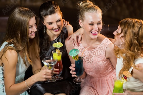 Female friends interacting with each other while having cocktail - Buy ...