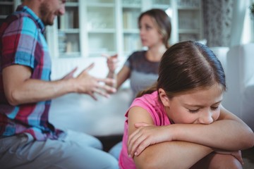 Sad girl listening to her parents arguing