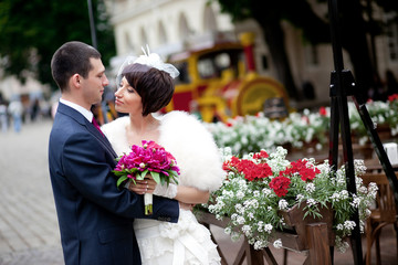 Wall Mural - Groom holds elegant bride in his hands while they hug before red