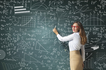 Young woman drawing charts and graphs on blackboard