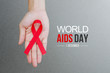 Female hands holding red ribbon HIV, AIDS awareness ribbon. World Aids Day concept.