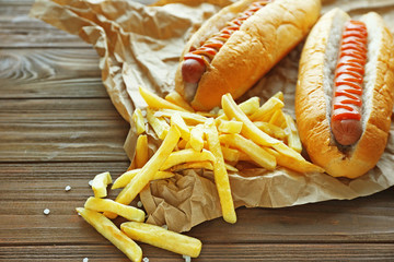 Wall Mural - Tasty hot dogs and fries on wooden background