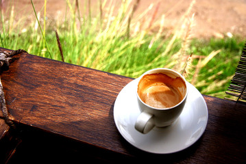 hot coffee  on wooden balcony with grasses background.