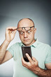 Image of an expressive middle aged man looking at his cell phone