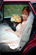 © IVASHstudio - Look from the outside at pretty bride sitting in red car