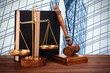 Gavel with books and scales on modern skyscraper background