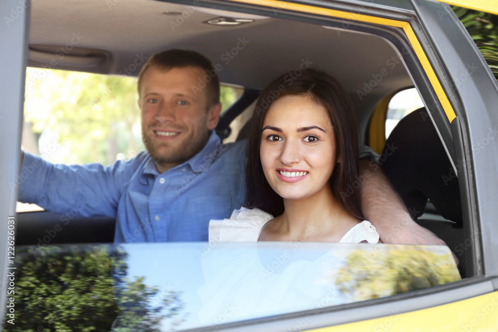 Beautiful couple sitting on backseat in car