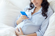 © Syda Productions - close up of pregnant woman with smartphone in bed