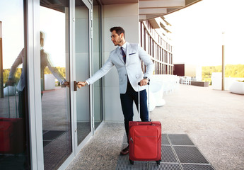 Full length portrait of young executive with a suitcase.