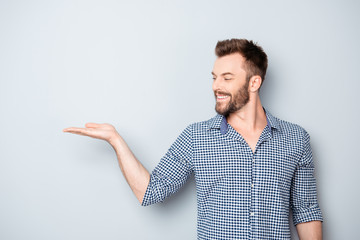 Wall Mural - Portrait of young man showing product isolated on gray backgroun