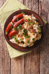 Wall Mural - Dutch stamppot of potatoes, cabbage and carrots, with sausages closeup on a plate. vertical top view