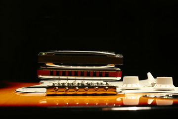 Vintage electric guitar with harmonica on black background