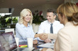 © sepy - Handshake. Shot of an investment manager shaking hands with smiling woman while consulting with middle aged couple about financial savings.