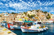 Old Fishing Boats At Simi , The Background Of Beautiful Multi-colored Buildings In The Island