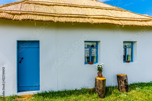 Fotografie, Obraz View of the peasant house with whitewall and reed roof. A door a