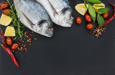 Two fresh dorado fish on black slate cutting board. Top view, copy space. 