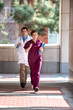© Eric Hood - Emergency room male doctor and female nurse practitioner running down outdoor in hospital corridor