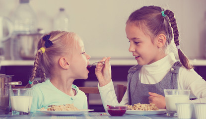 Two cheerful girls eating healthy oatmeal