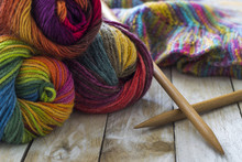 Colorful Skeins Of Wool With Knitting Needles And Sweater On Wooden Background