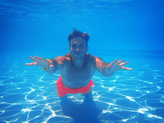 Poster - Sporty young man swimming underwater in pool