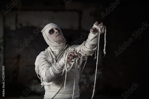 Zdjęcie XXL Portret młodego mężczyzny ubranego w kostium Halloween Mumia. Jest gotowy na przyjęcie z okazji Halloween w ciemnym domu z nawiedzonymi domami.