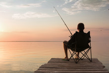 Fisherman With Rod Over The Lake At Sunset