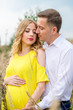 © demchyna - Portrait man and beautiful pregnant woman in a yellow dress with long blond hair. Photo session at nature