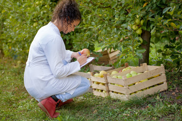 happy young woman agronomist with green apple in her hand