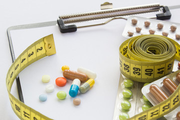 Wall Mural - clipboard with colored pills and yellow centimeter tape