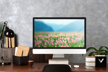 Sticker - Comfortable workplace with modern computer and field of beautiful blooming tulips on screen