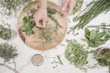© Mint Images - Overhead view of a woman preparing herbs and plants for use in cooking. Rosemary, chives, mint and coriander seeds.