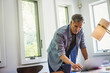 © Mint Images - A man at home using a laptop on a desk.