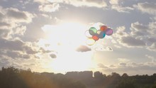 Young Child Releases All Her Balloons As They Float Into The Sky, In Slow Motion