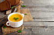 Tasty pumpkin soup with potatoes and rice. Pumpkin soup in a bowl, spoon, brown bread slices on old wooden background with empty place for text