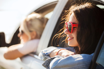 Wall Mural - happy teenage girls or women in car at seaside