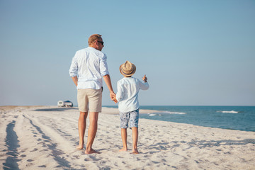 Wall Mural - Father with son walk on deserted sea beach