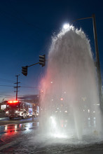 Water Geyser From Broken Fire Hydrant With Fire Truck At Sunset