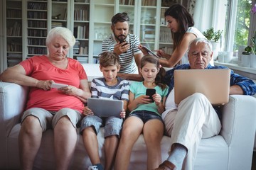 family using laptop, mobile phone and digital t