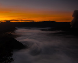 Wall Mural - The fog creeps over the water under an orange sky (Bohorok, Indonesia)