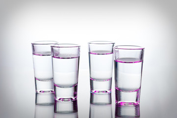 Vodka color shots filled with alcohol on glass bar table