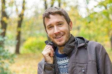 Young, cheerful man is happy in the park in autumn when leaves become colorful.