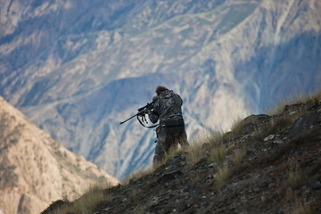 hunter in camouflage looks into the optical sight