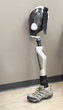 Leg prosthesis with shoe, leaning against a wall