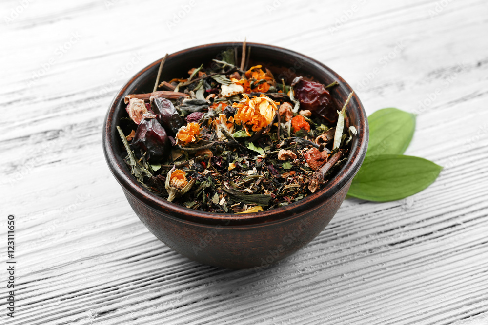 Dried tea in bowl on wooden background