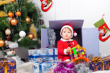 Cute little girl in Santa's suit near a Christmas tree